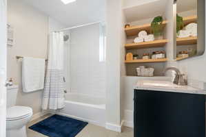 Bathroom featuring a dark vanity with a light speckled countertop, an undermount sink,  a contemporary faucet and custom tile surround