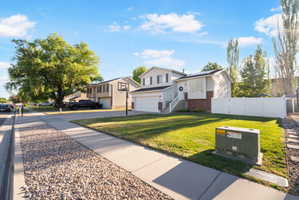 Two-story property featuring a white vinyl fence, attached two-car garage, and a lush green lawn