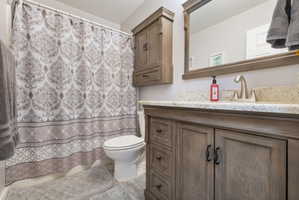 Bathroom featuring wood-finish vanity with stone countertop, undermount sink, and framed mirror