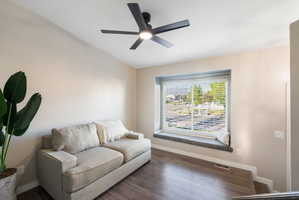 Spacious room featuring wood-finish flooring, a contemporary ceiling fan with integrated lighting, and a large window