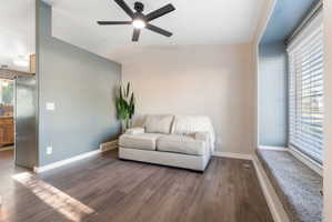Living area featuring wood-finish flooring, a contemporary ceiling fan with integrated lighting, a contrasting accent wall