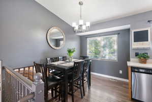 Dining area featuring wood-finish flooring, a contemporary light fixture, and a large window