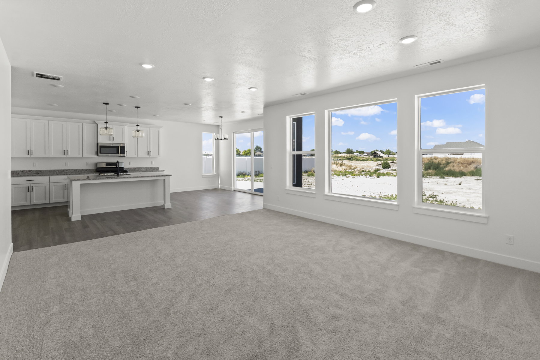 Open-concept living space, a kitchen with white cabinetry and recessed lighting