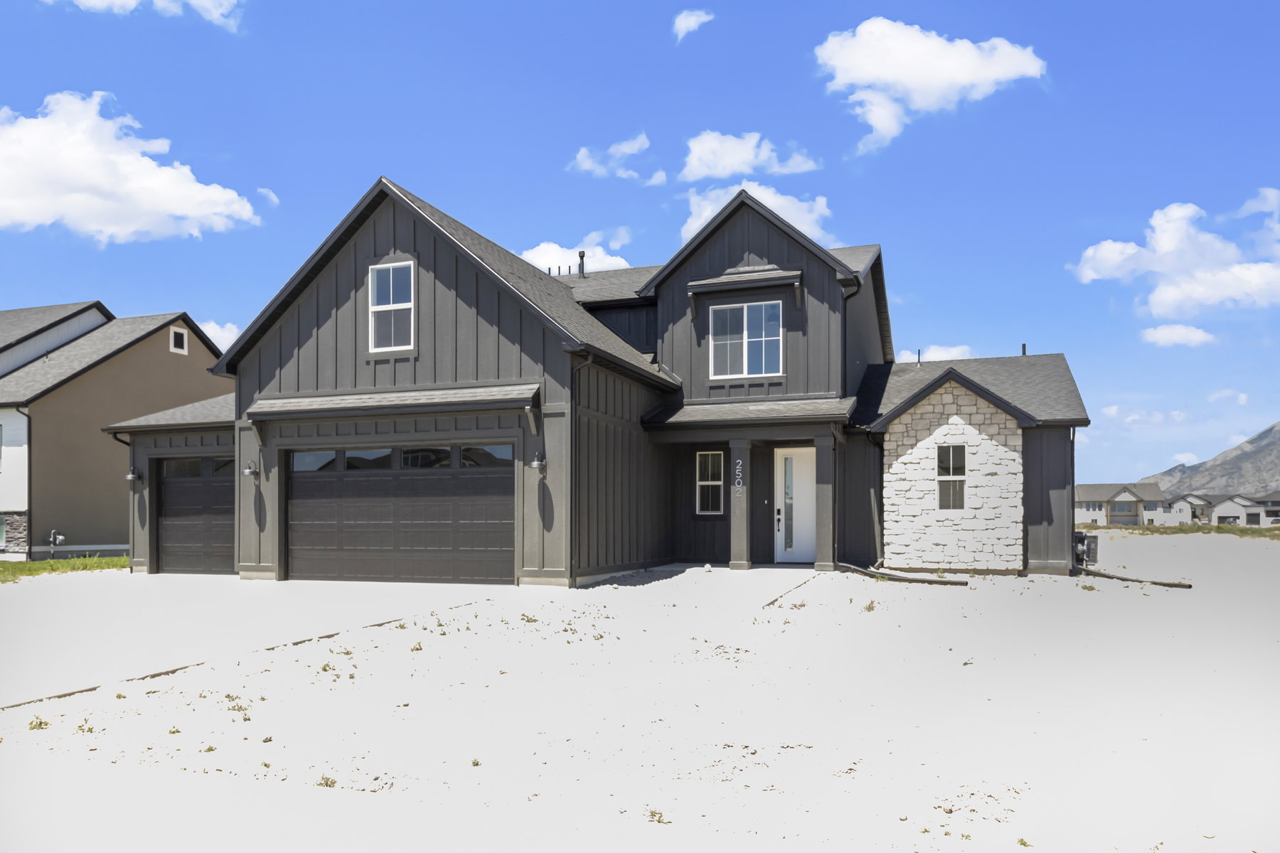 Modern farmhouse-style exterior featuring dark vertical siding and a light stone facade