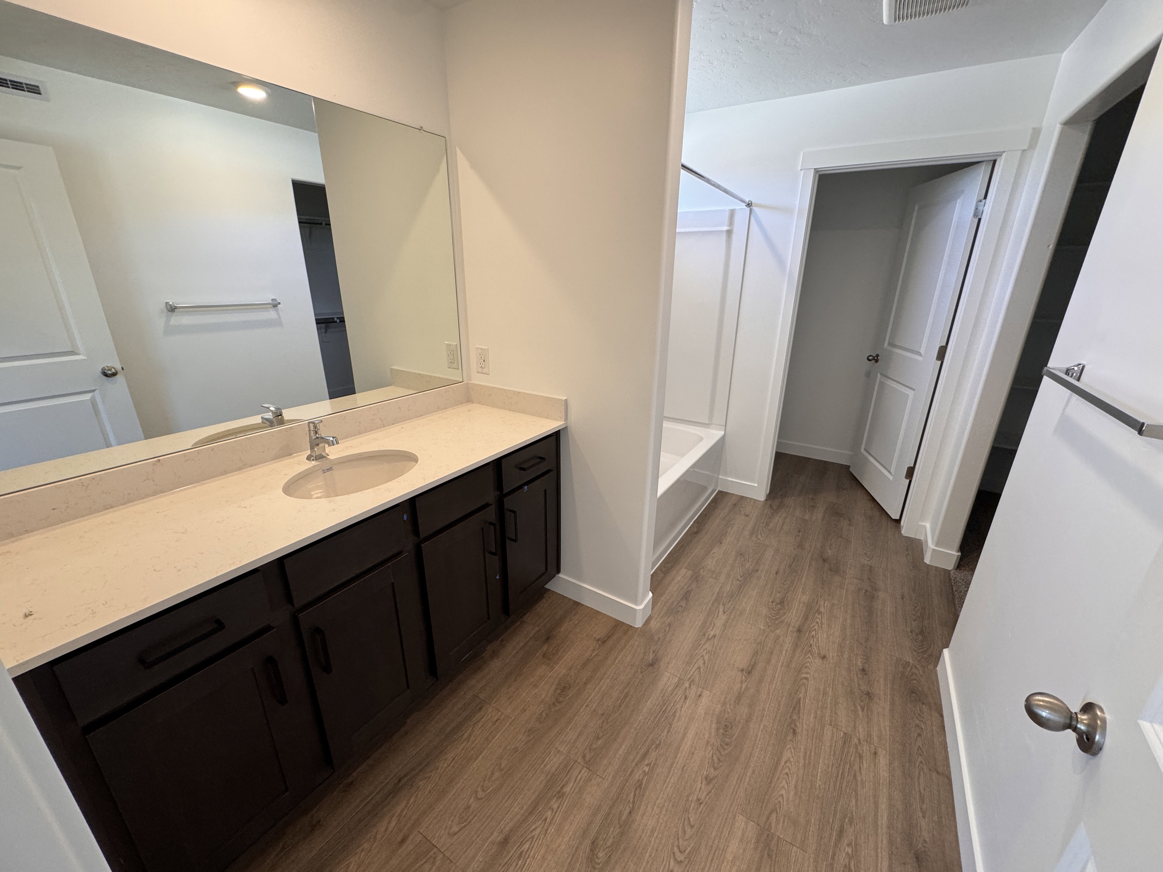 Bathroom vanity featuring a single basin sink, light-colored countertop, and dark wood-finish cabinetry
