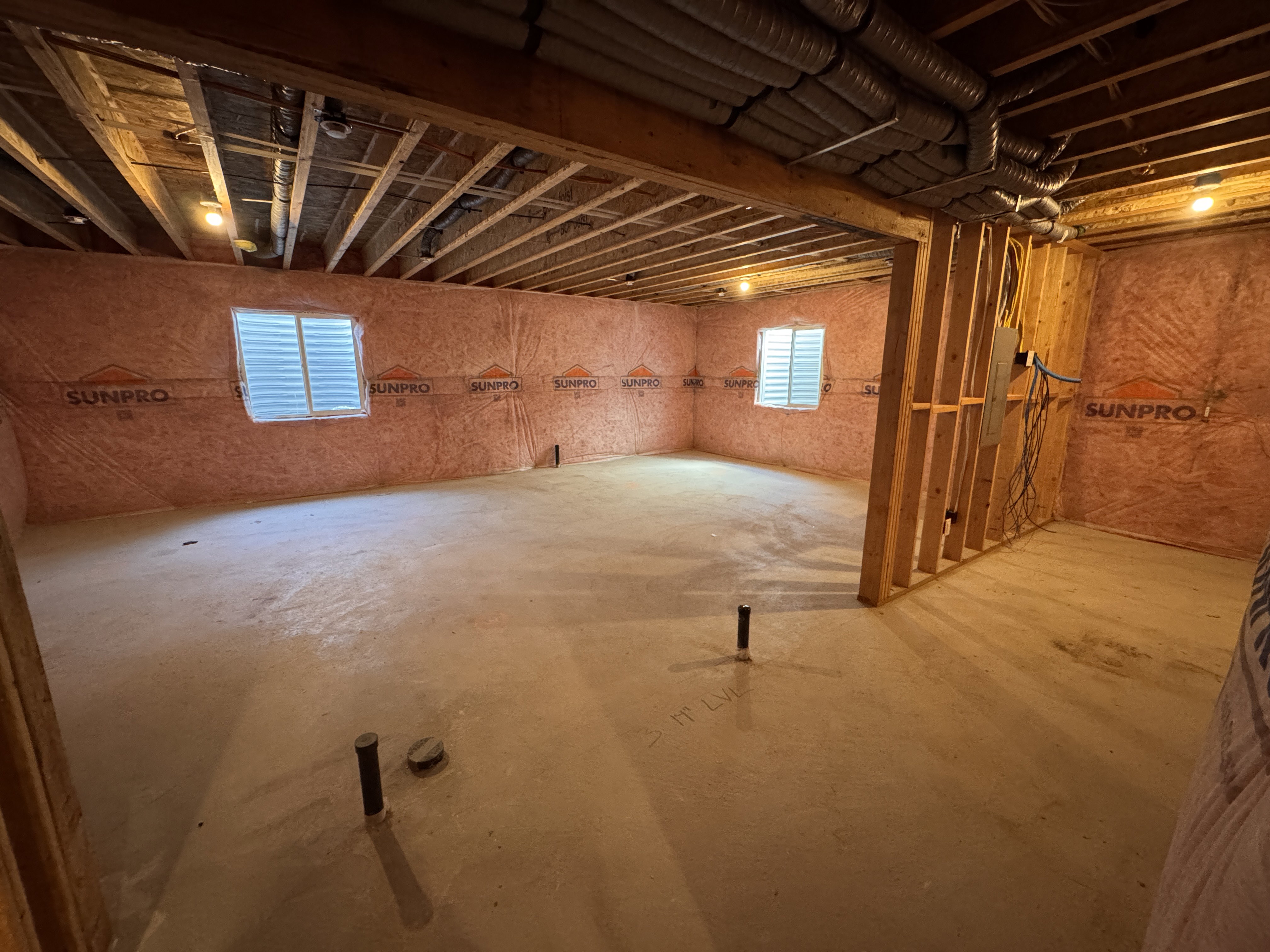 Unfinished basement offering exposed ceiling joists, concrete flooring, two windows with horizontal blinds, and exposed insulation