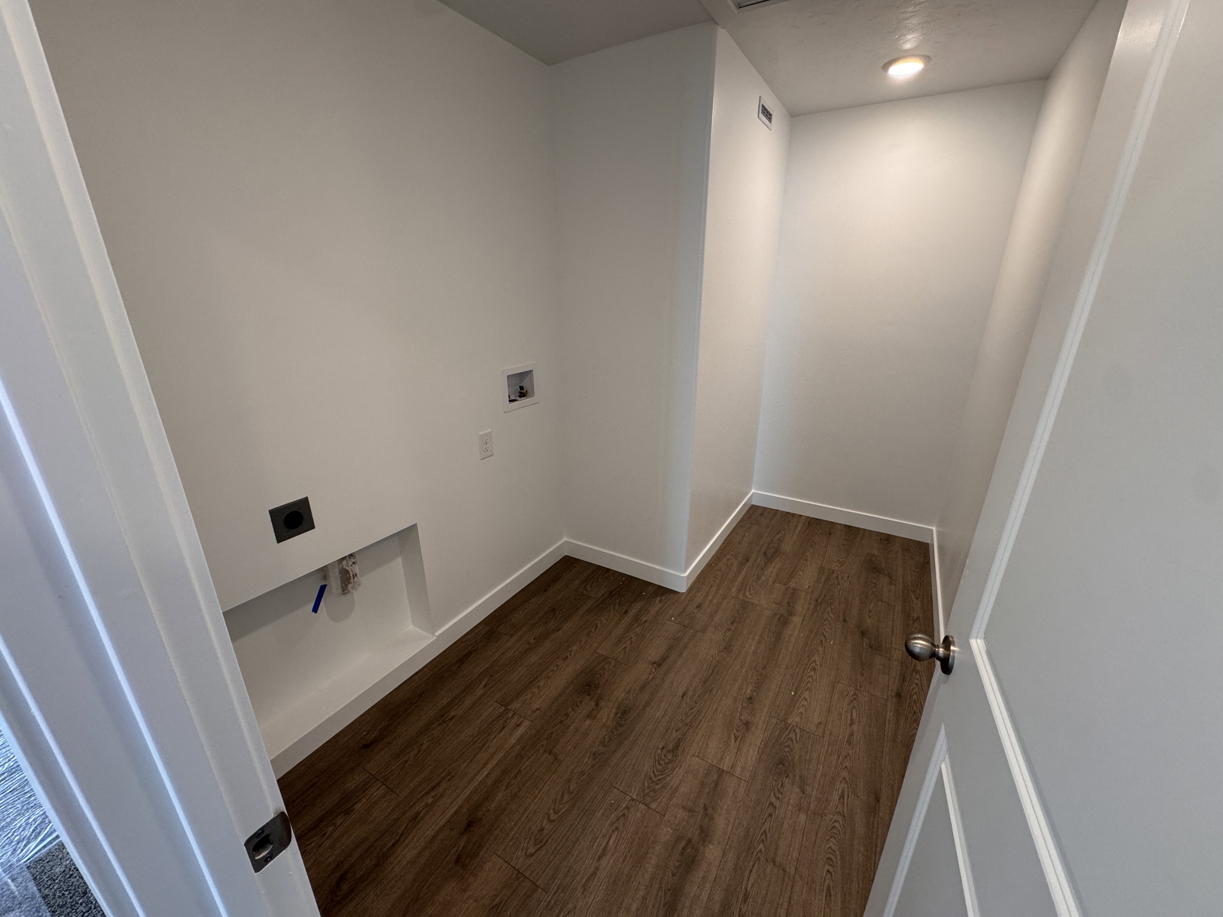 Dedicated utility space featuring wood-finish flooring, recessed lighting, and bright white baseboards