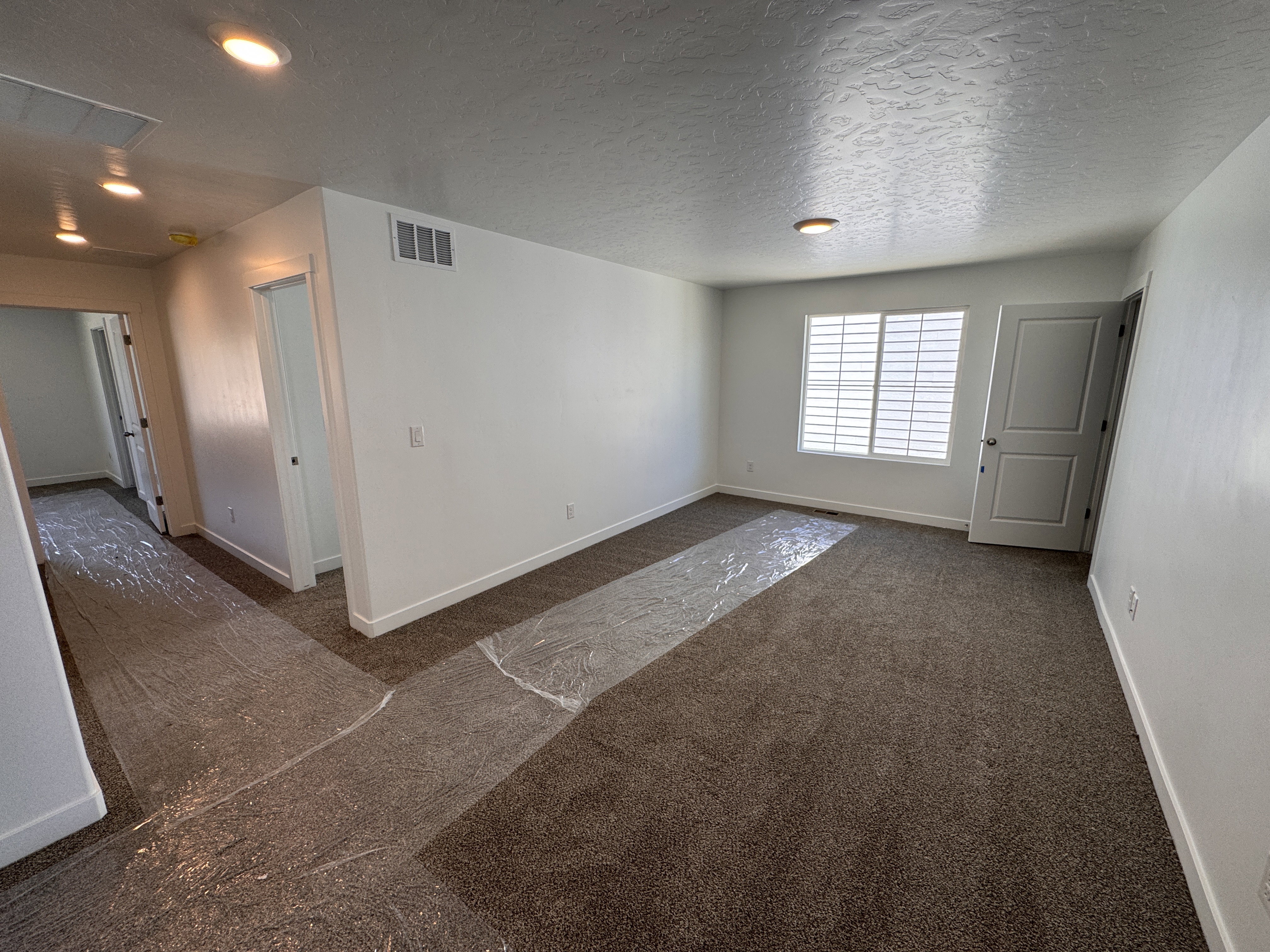 Carpeted interior space with a white door and window featuring horizontal blinds