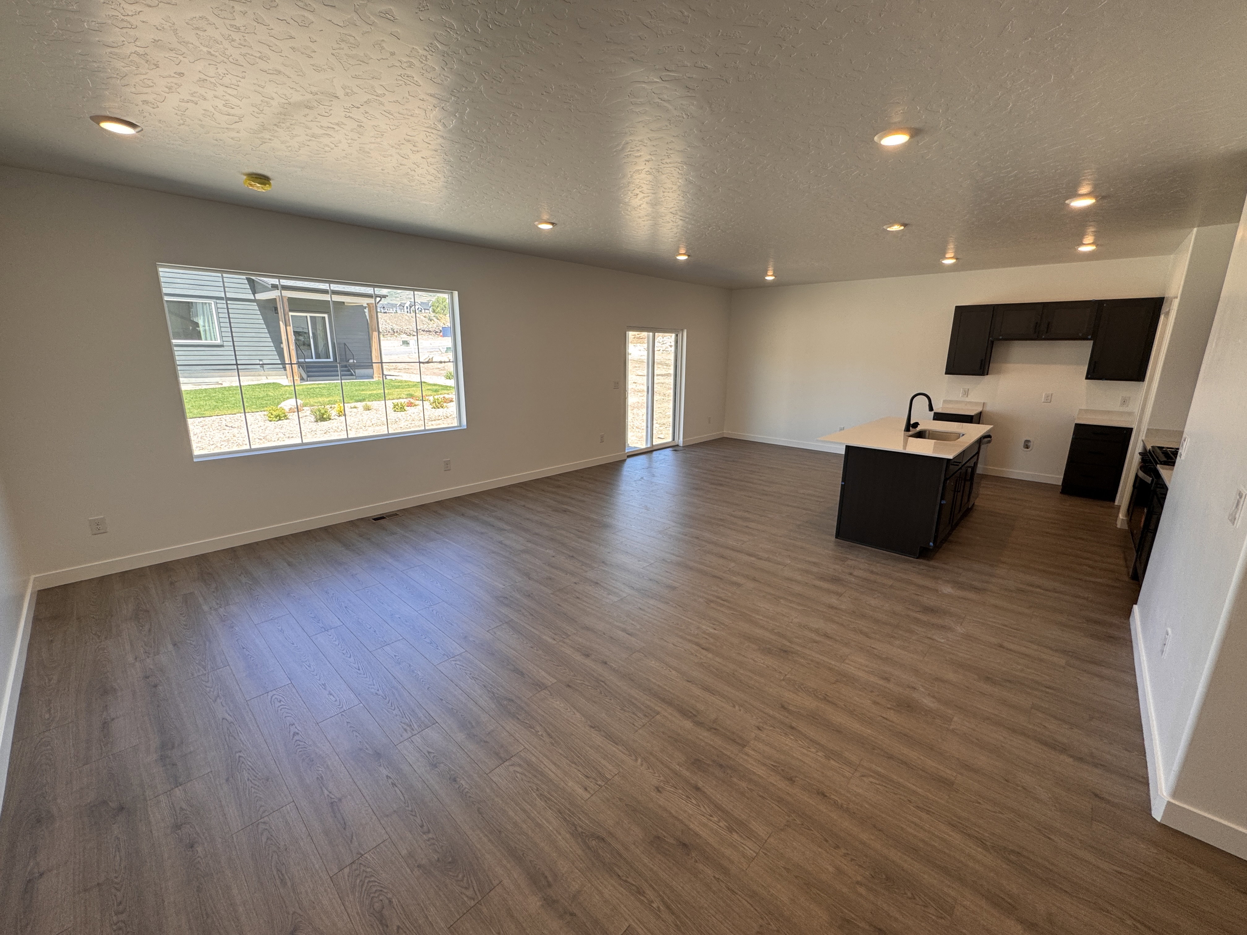 Open-concept living space featuring wood-finish flooring, recessed lighting, and a sliding glass door providing outdoor access