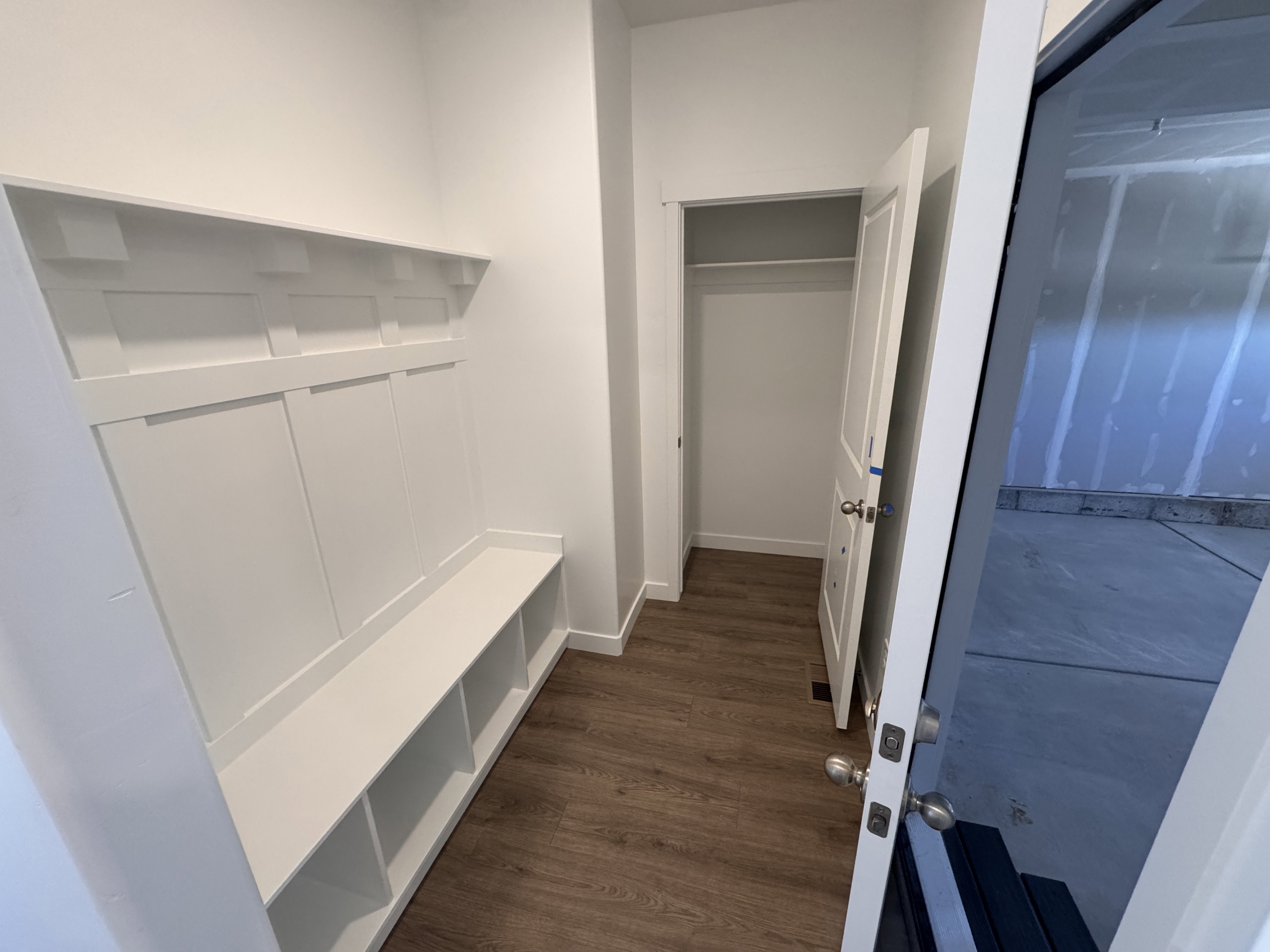 Entry mudroom featuring built-in white cabinetry, a bench with integrated storage cubbies, and wood-finish flooring