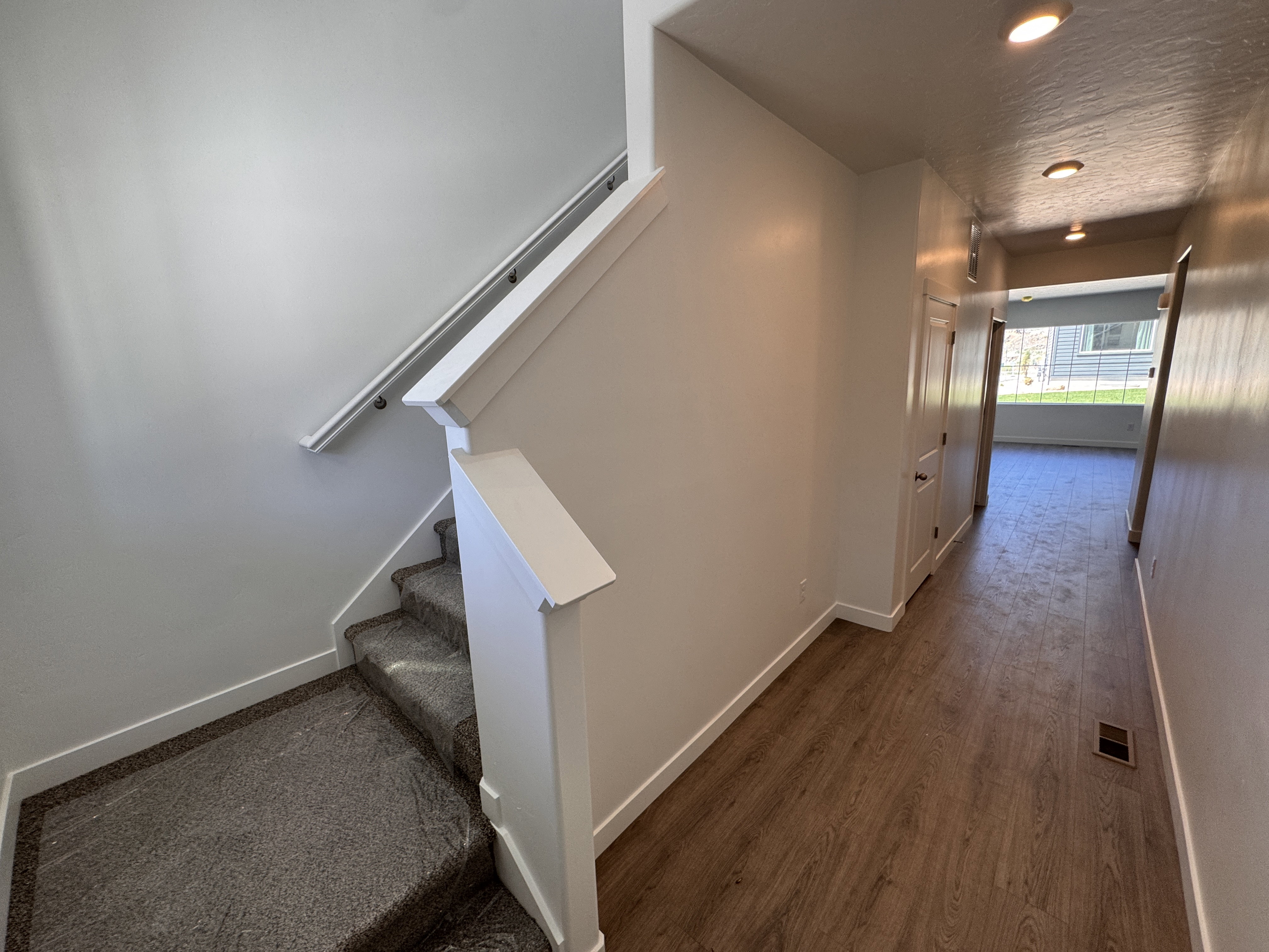 Entryway featuring wood-finish flooring, recessed lighting, and a staircase with carpeted treads and white handrails