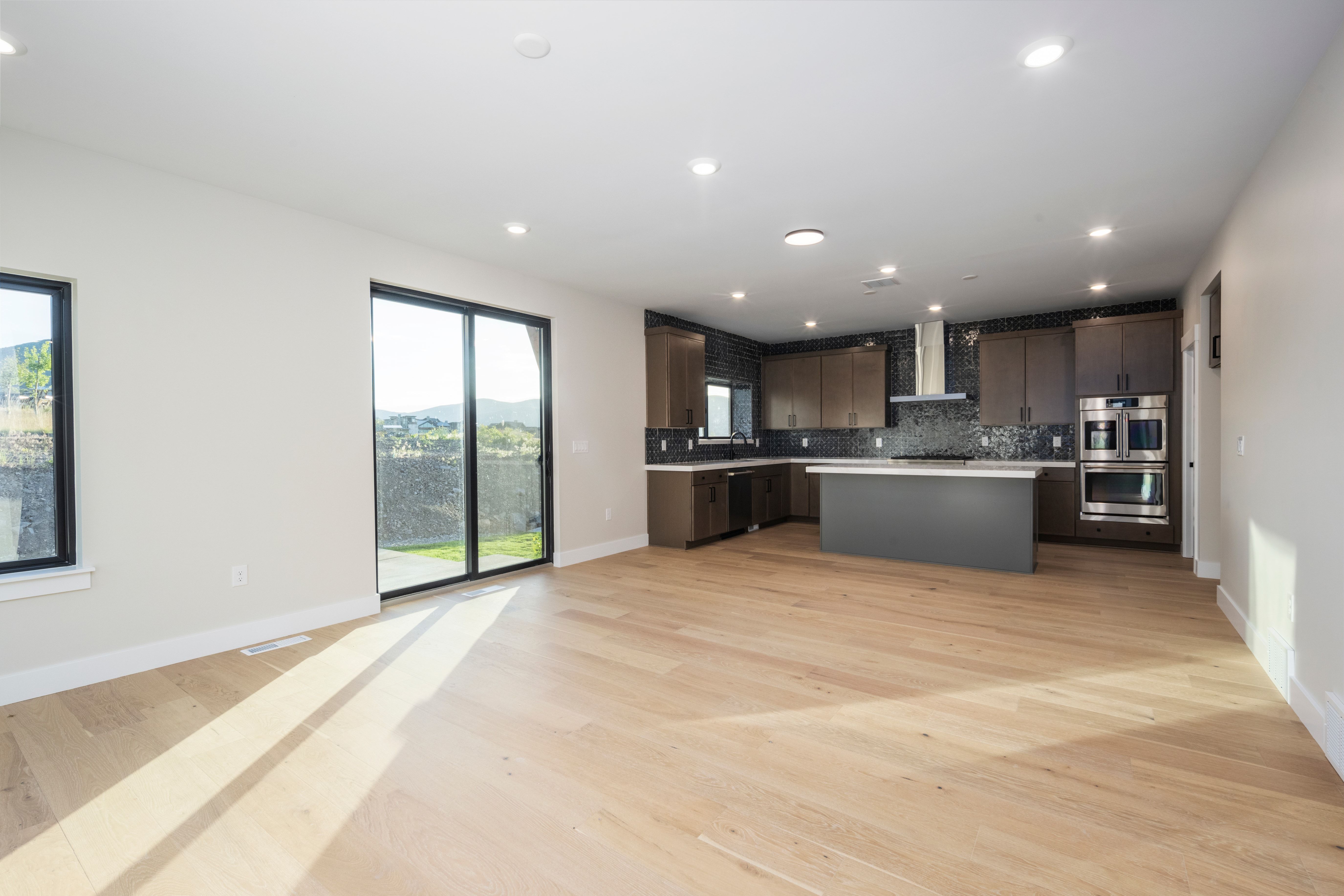Open-concept living area with light wood-finish flooring, recessed lighting, and expansive sliding glass doors