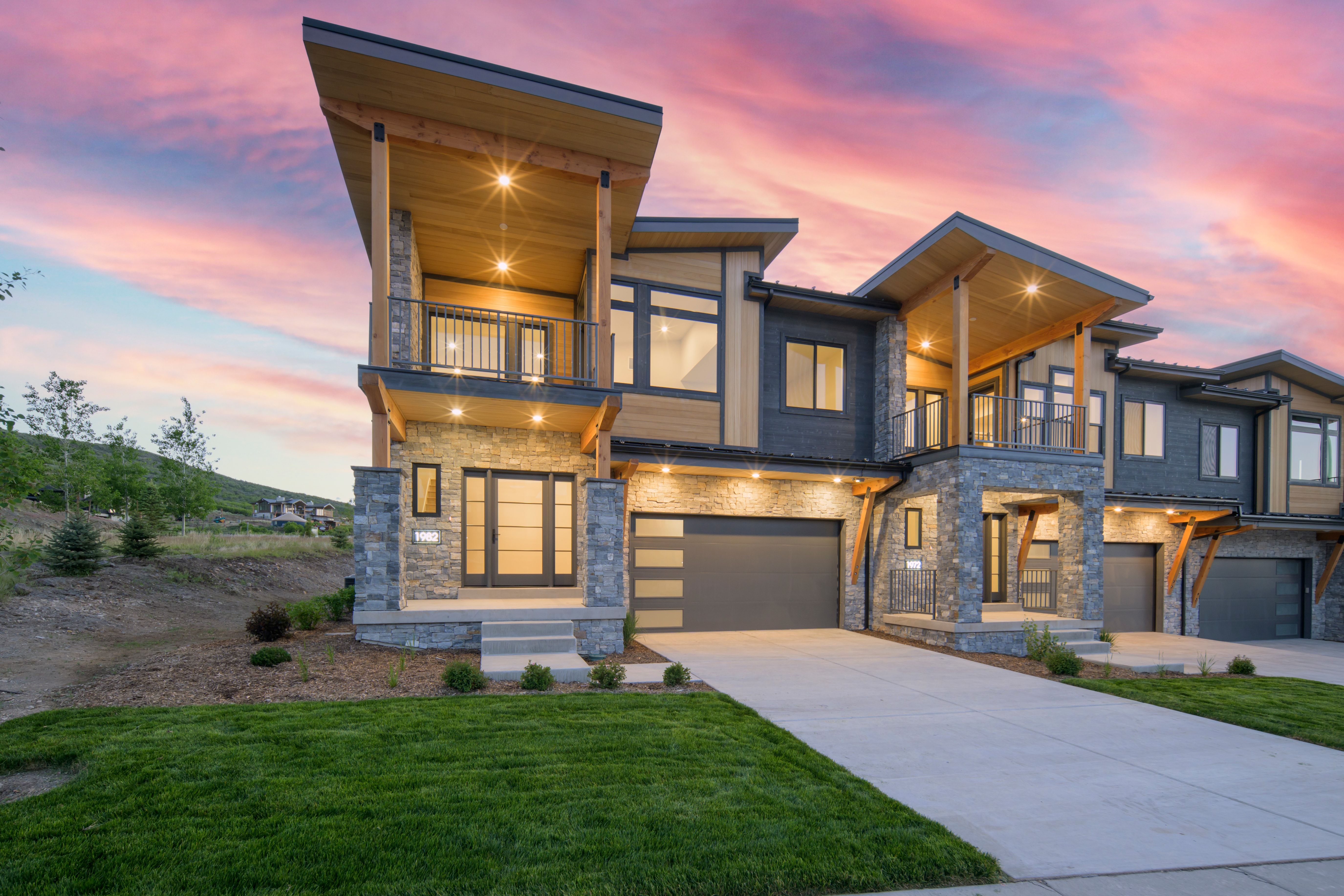 Contemporary multi-level exterior featuring stone cladding, wood-finish siding, and large windows