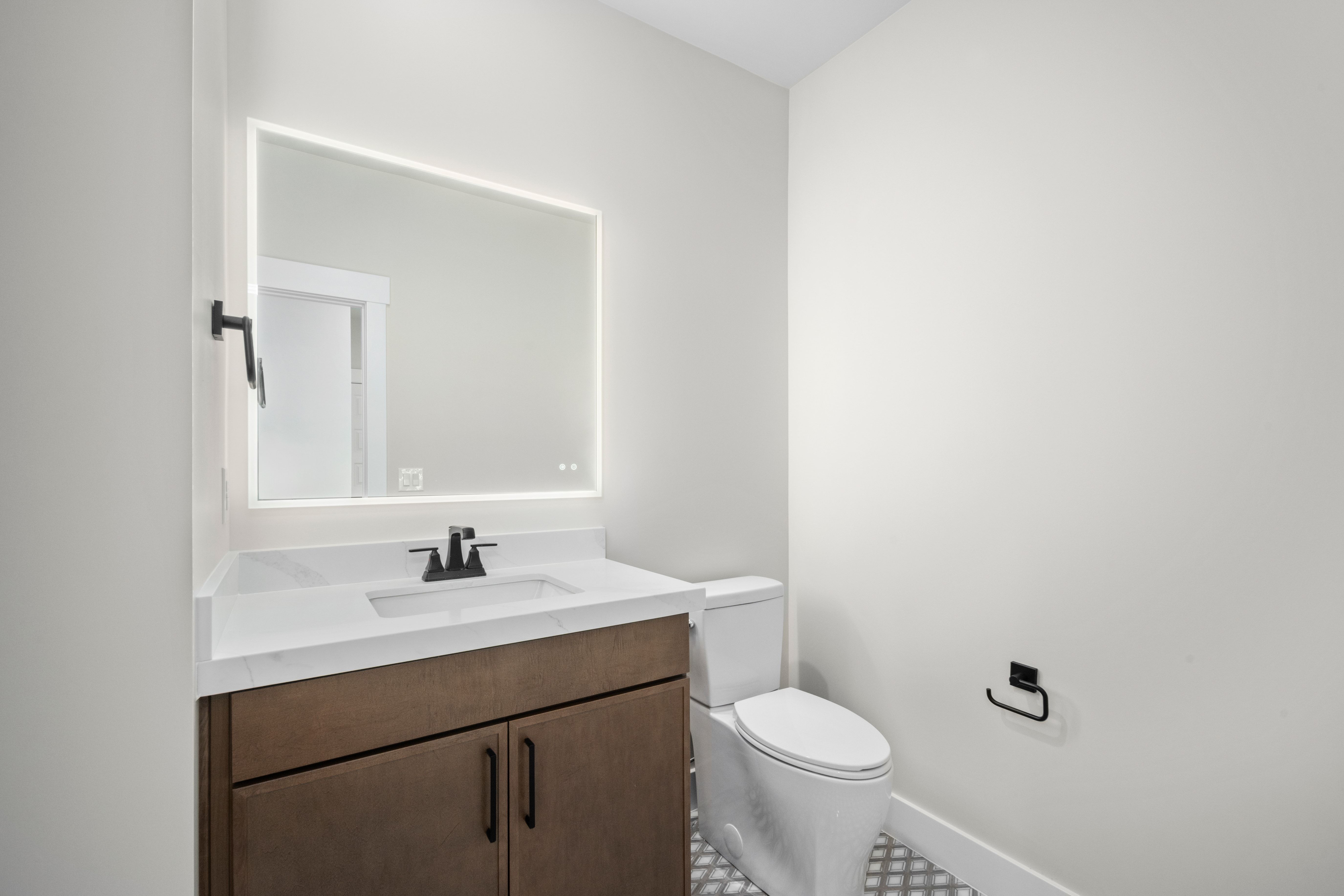 Modern vanity featuring a built-in sink, white stone-finish countertop, and rich wood-finish cabinetry with matte black hardware