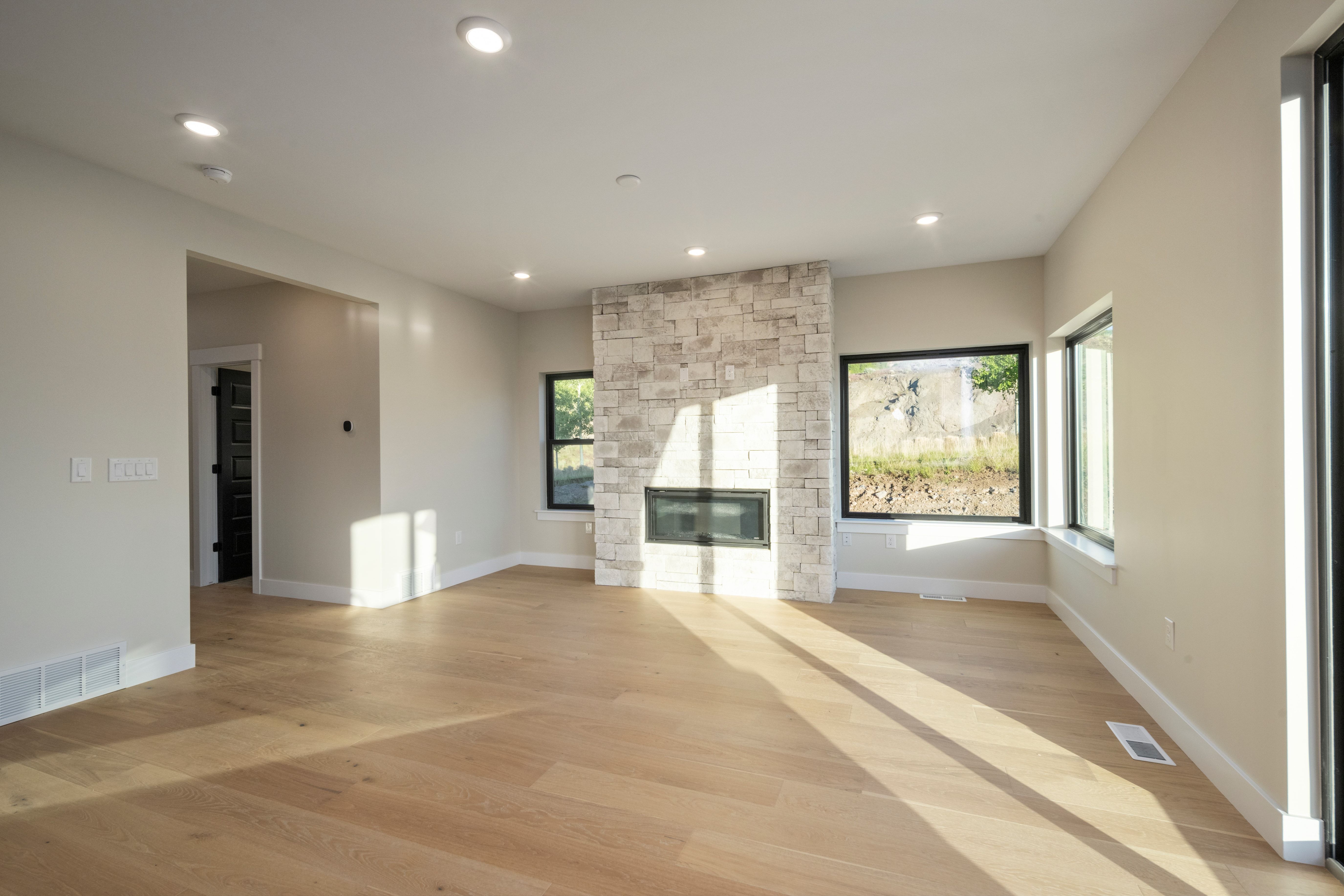 Spacious room featuring light wood-finish flooring and recessed lighting