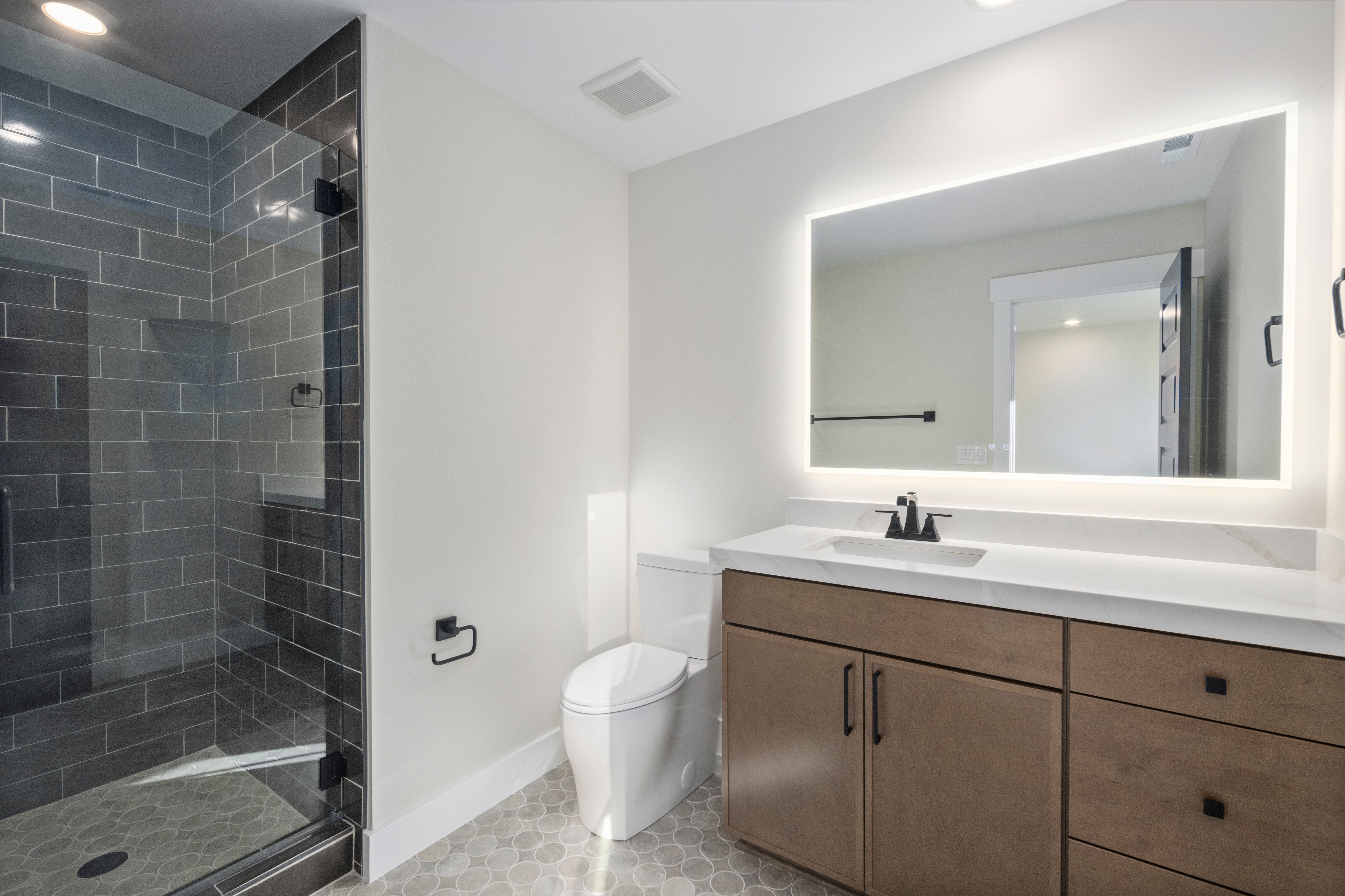 Modern bathroom featuring a glass-enclosed shower with subway tile surround and hexagonal floor tile