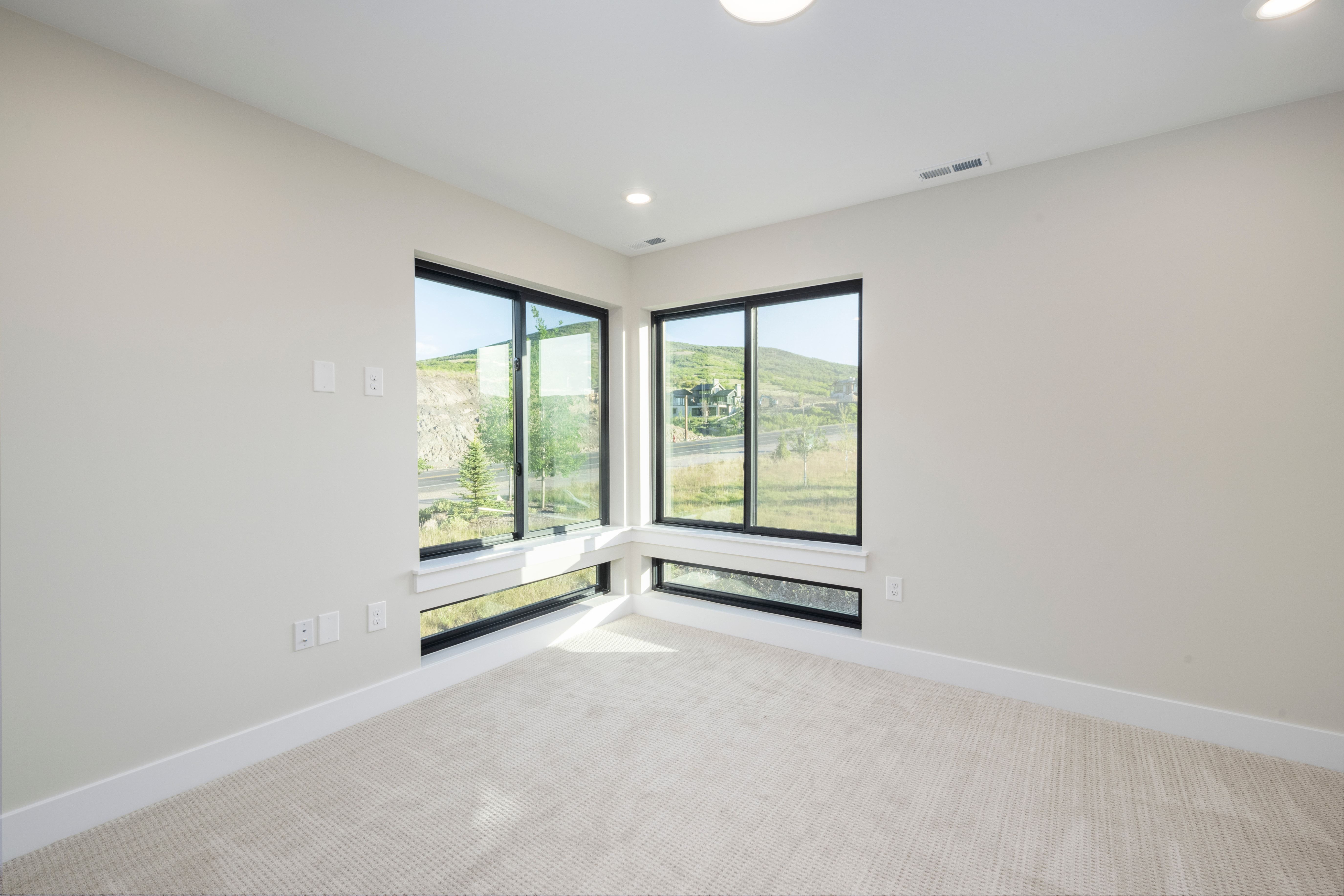 Corner window configuration with expansive mountain scenery, neutral carpeting, recessed ceiling lighting, and white baseboards