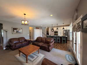 Open-concept living area featuring a kitchen with stainless steel appliances, white cabinetry, and a central island with bar seating