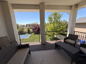 Covered outdoor deck with dark wood-finish flooring, white ceiling panels, and substantial support columns