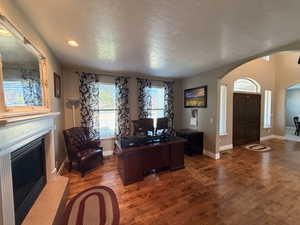 Spacious interior with wood-finish flooring, a decorative fireplace with a mantel, and recessed lighting
