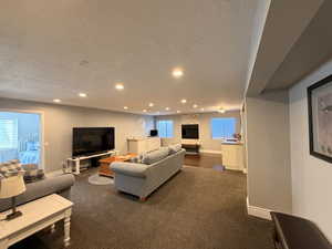 Expansive open-concept room featuring recessed lighting, a built-in fireplace with a stone surround, and wood-finish flooring