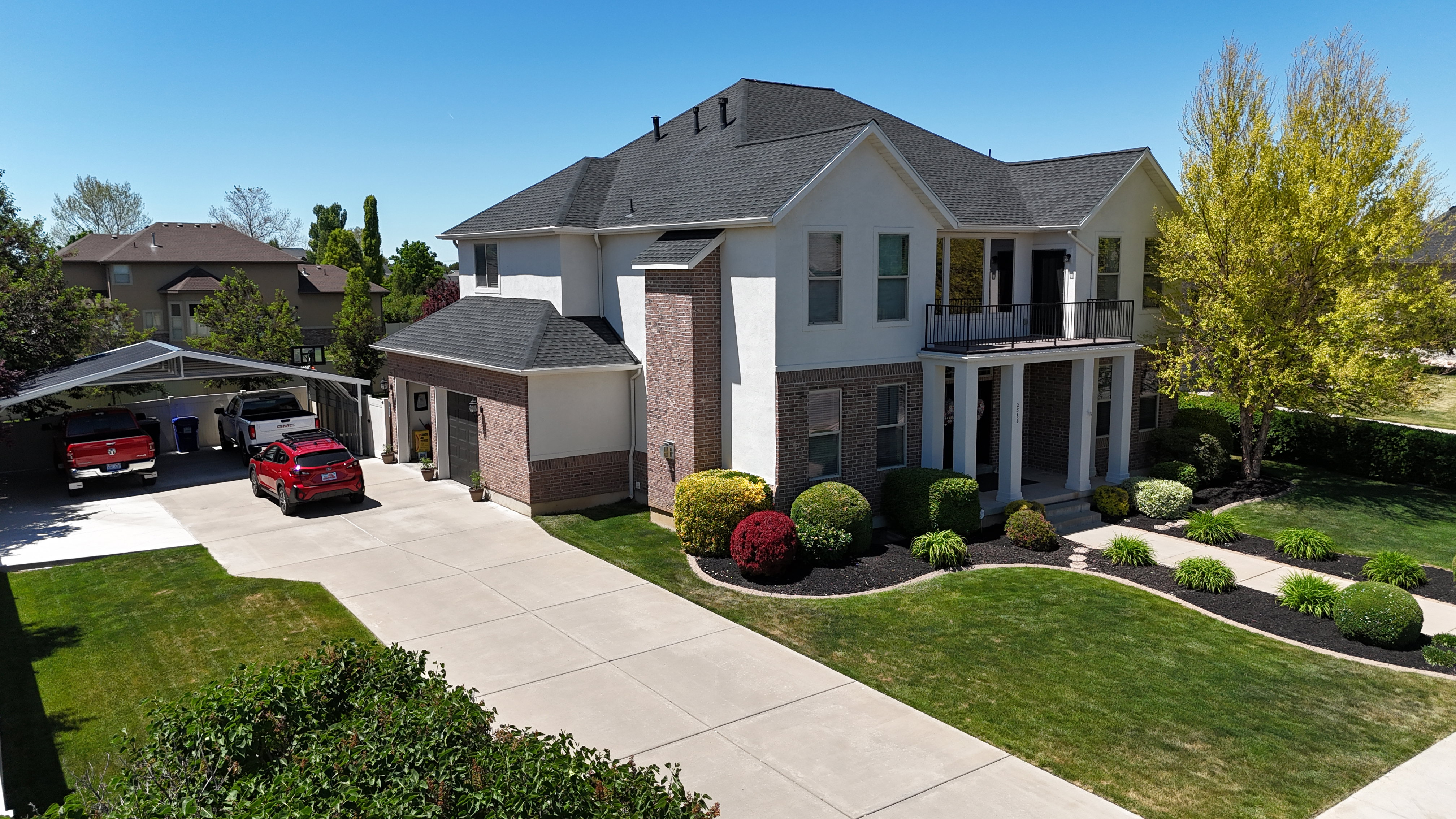 Stately two-story residence featuring a dark shingle roof and a combination of light-colored stucco and brick siding