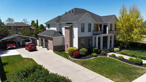 Stately two-story residence featuring a dark shingle roof and a combination of light-colored stucco and brick siding