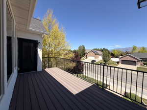 Spacious outdoor deck featuring composite decking, black metal railings, and an exterior door with a wall-mounted light fixture