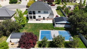 Expansive backyard featuring a multi-sport court with blue surfacing, a dedicated storage shed, mature trees, and a spacious rear patio