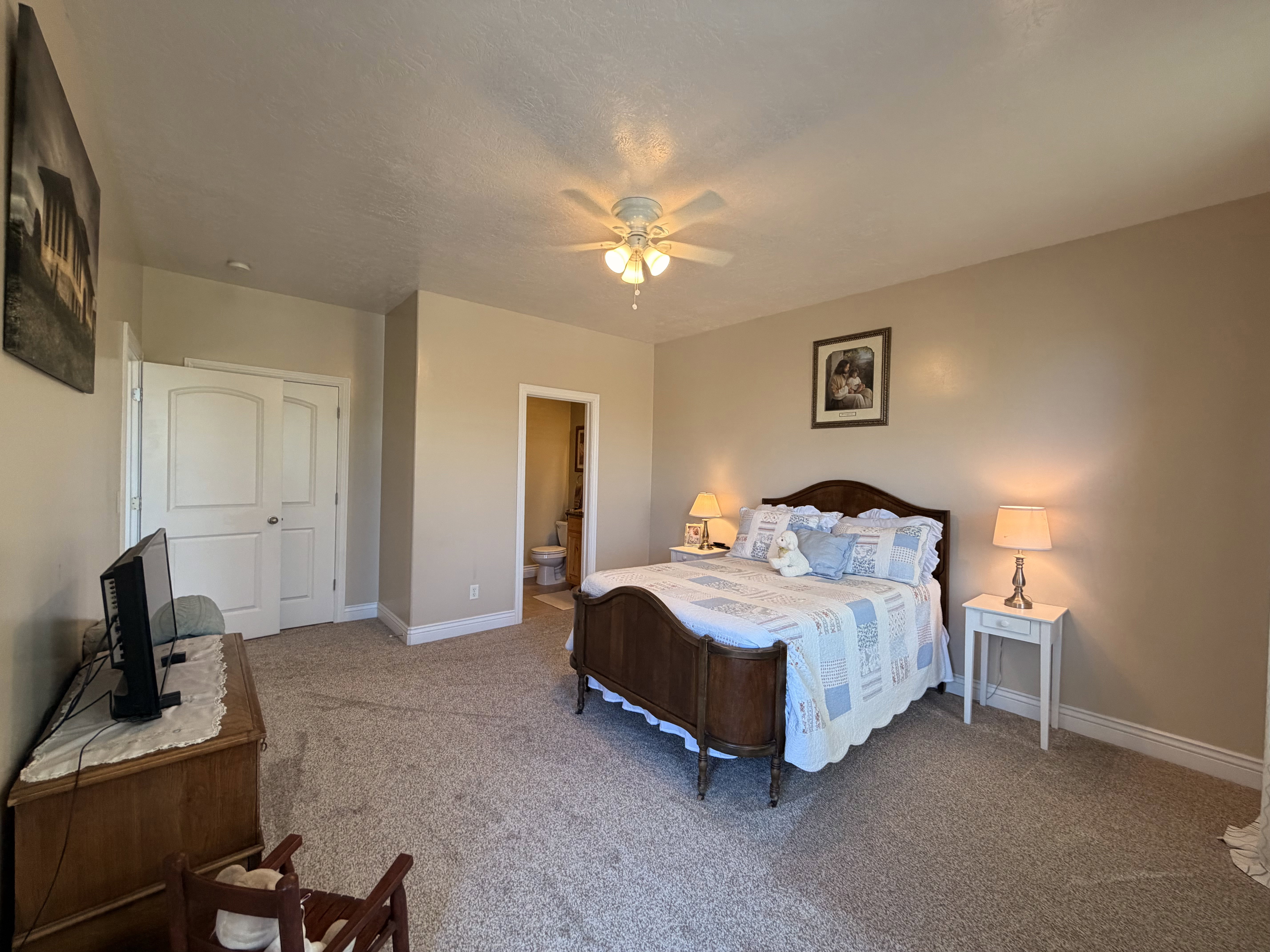 Carpeted bedroom featuring neutral wall tones and a ceiling fan with integrated lighting