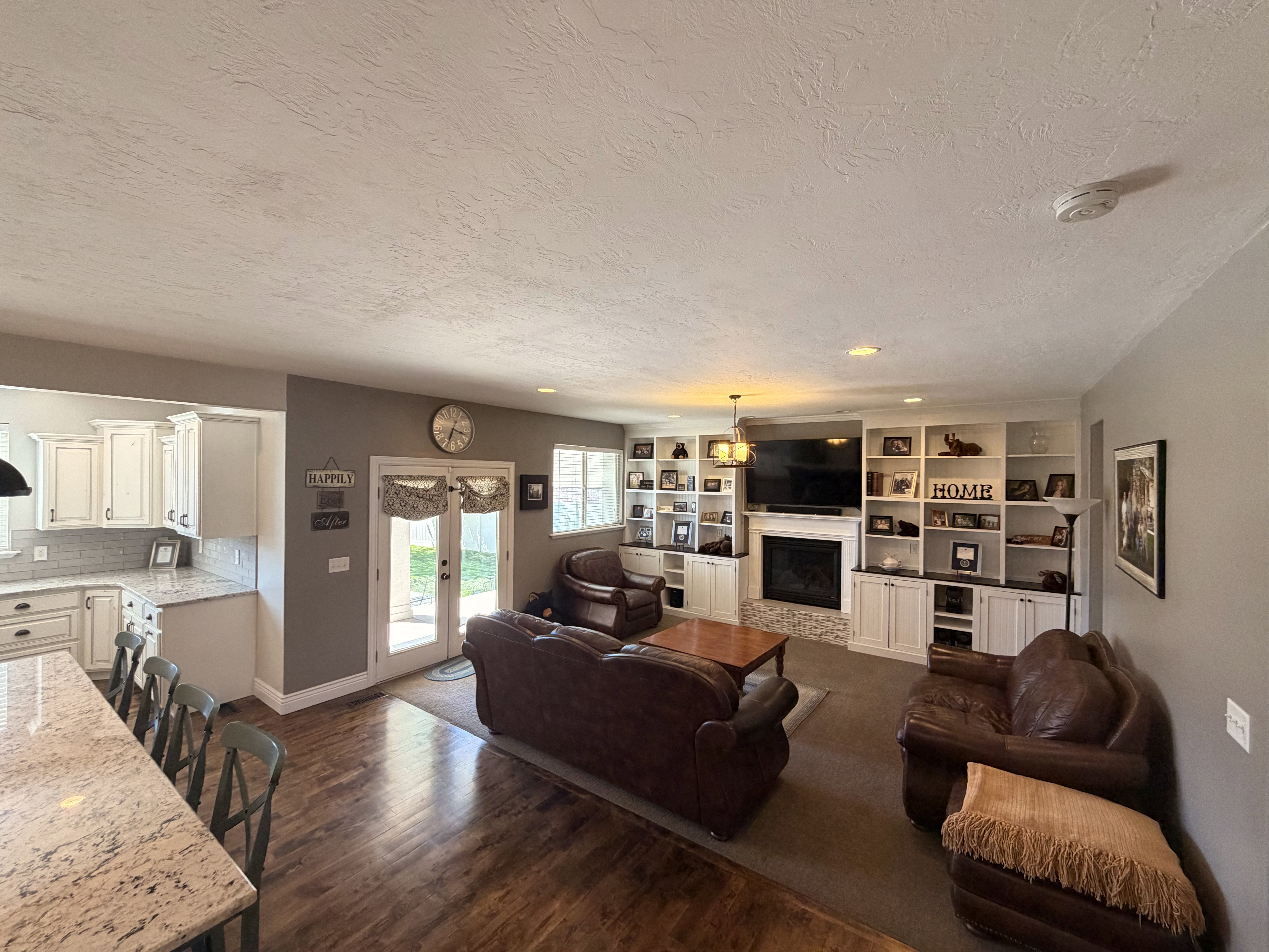 Spacious living area featuring extensive built-in shelving, a fireplace with a stone surround, and wood-finish flooring