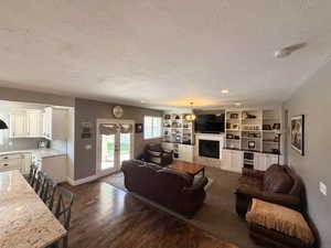 Spacious living area featuring extensive built-in shelving, a fireplace with a stone surround, and wood-finish flooring