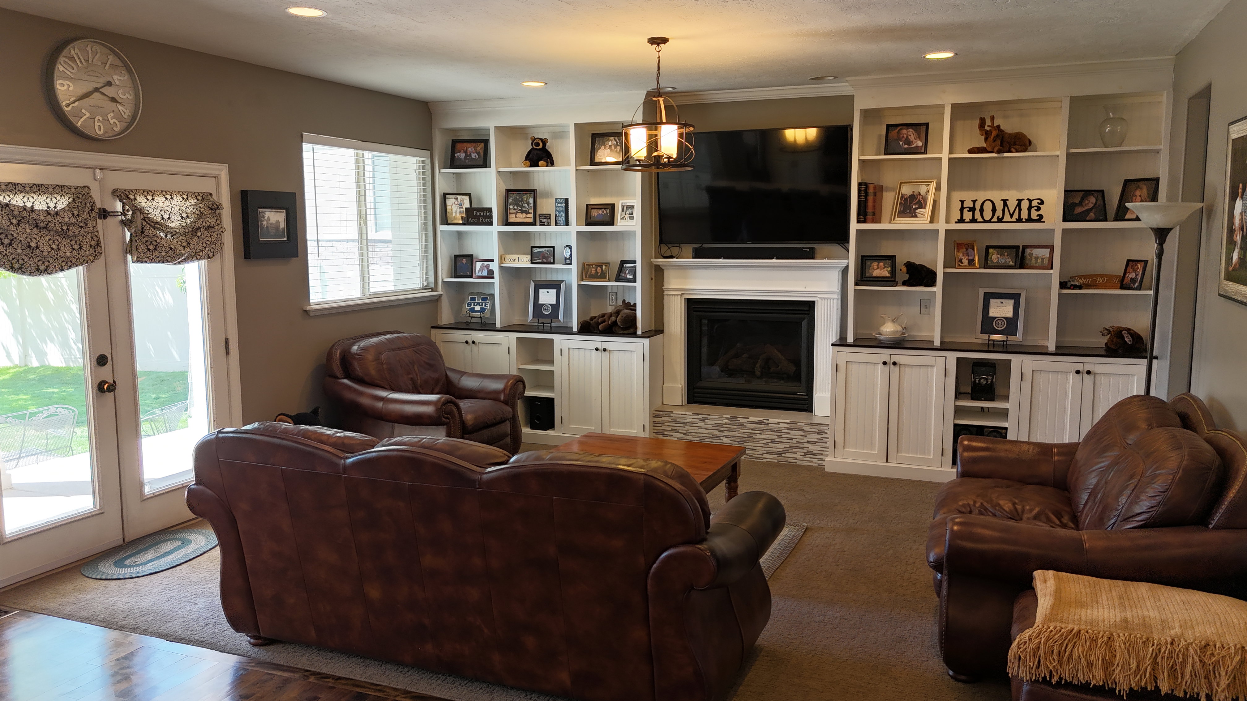 Living area featuring built-in shelving, a fireplace with a stone surround, and recessed lighting