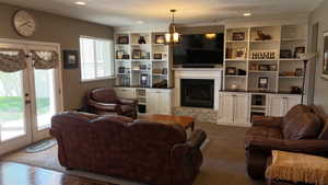 Living area featuring built-in shelving, a fireplace with a stone surround, and recessed lighting