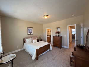 Carpeted bedroom featuring a flush mount ceiling light, neutral wall colors, white baseboards, and two doorways leading to interior spaces