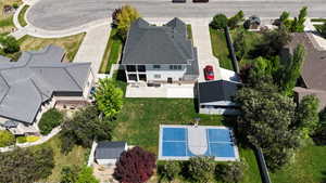 Expansive backyard featuring a blue-surfaced sports court, a manicured lawn, and mature trees
