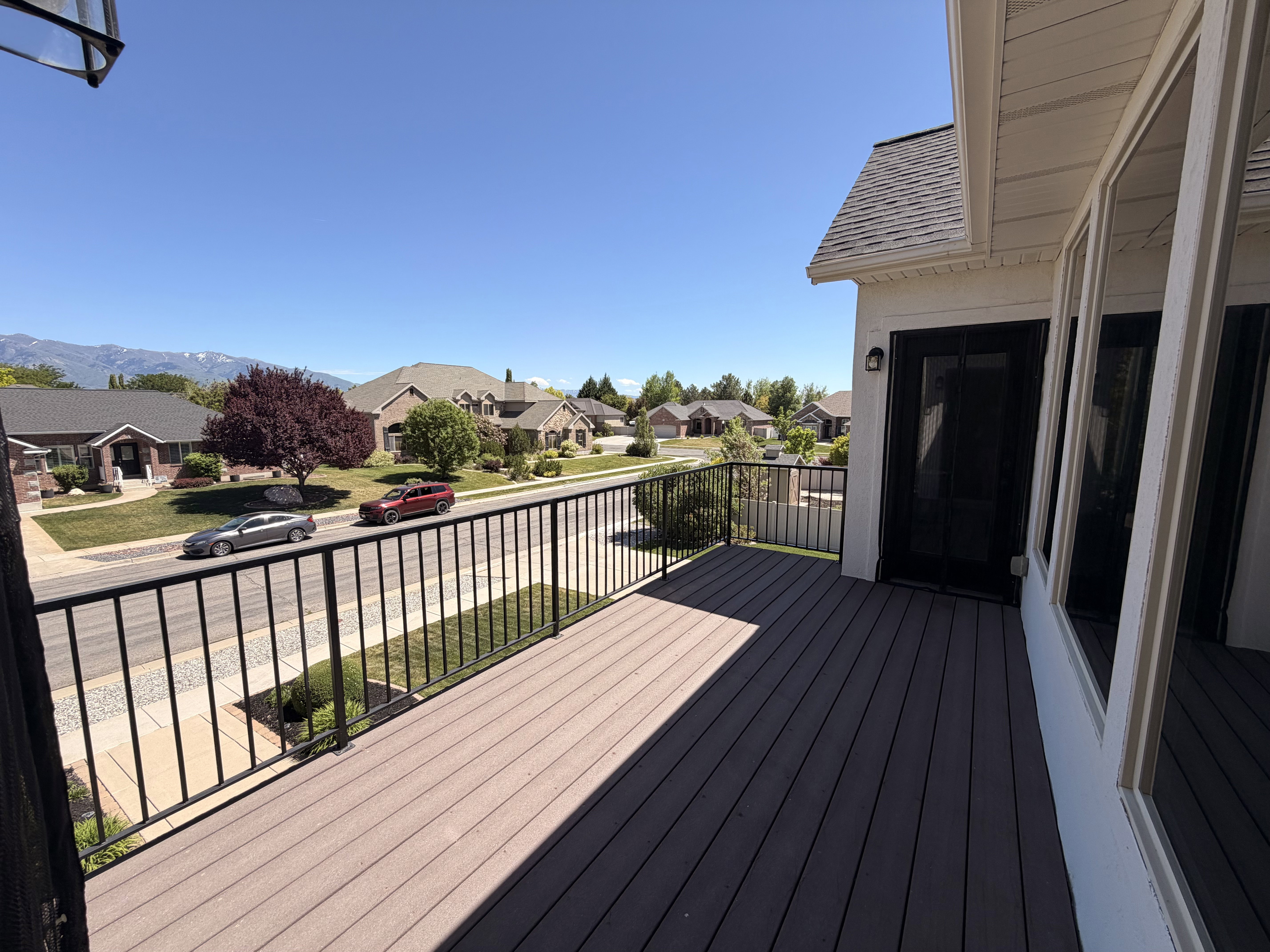 Outdoor balcony featuring wood-finish decking and black iron railings