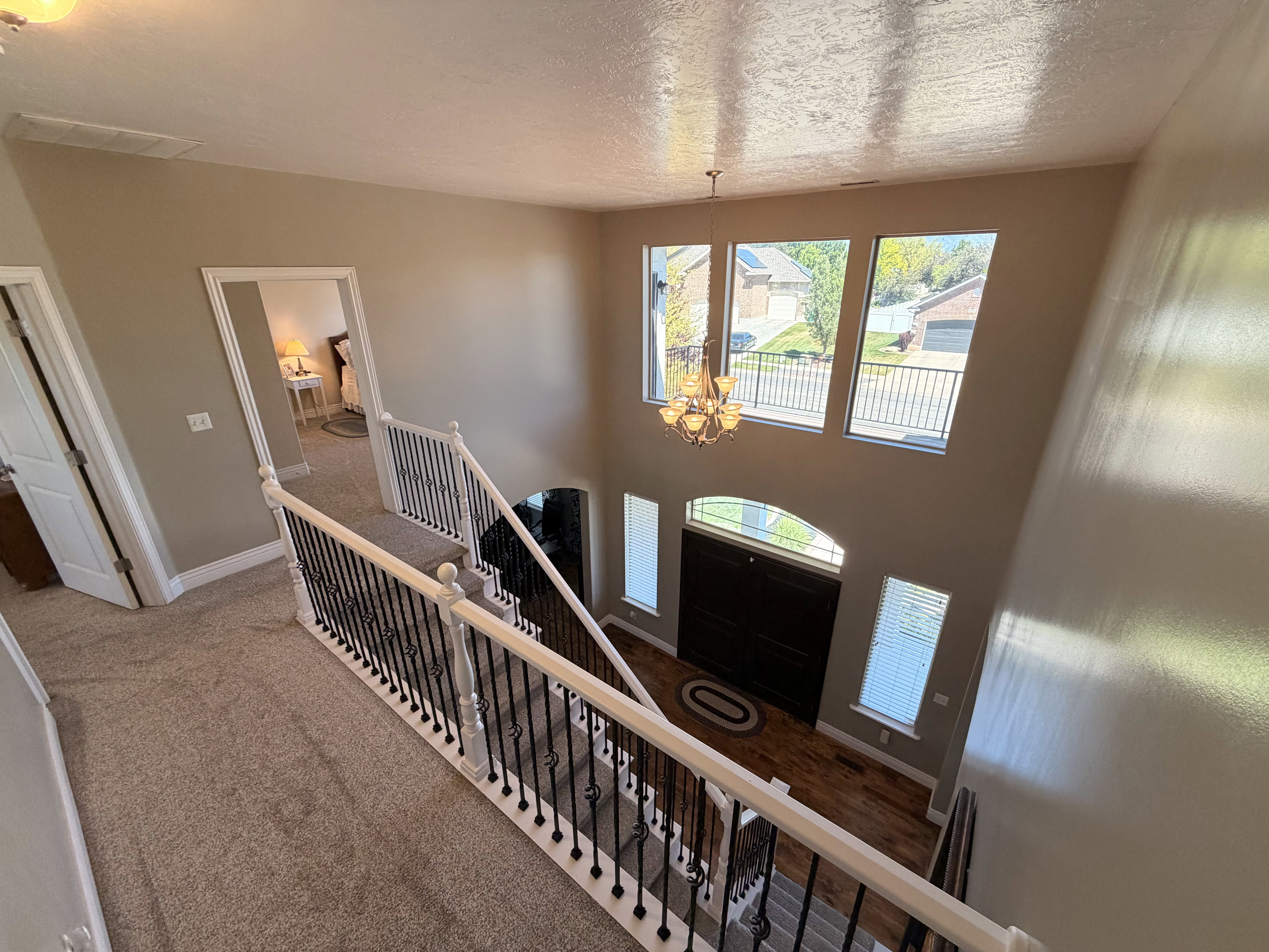 Two-story foyer featuring wood-finish flooring, a chandelier, and an arched transom window above the entry door