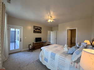 Carpeted room with a ceiling fan, direct outdoor access through a glass-paneled door, and a doorway opening to an additional room