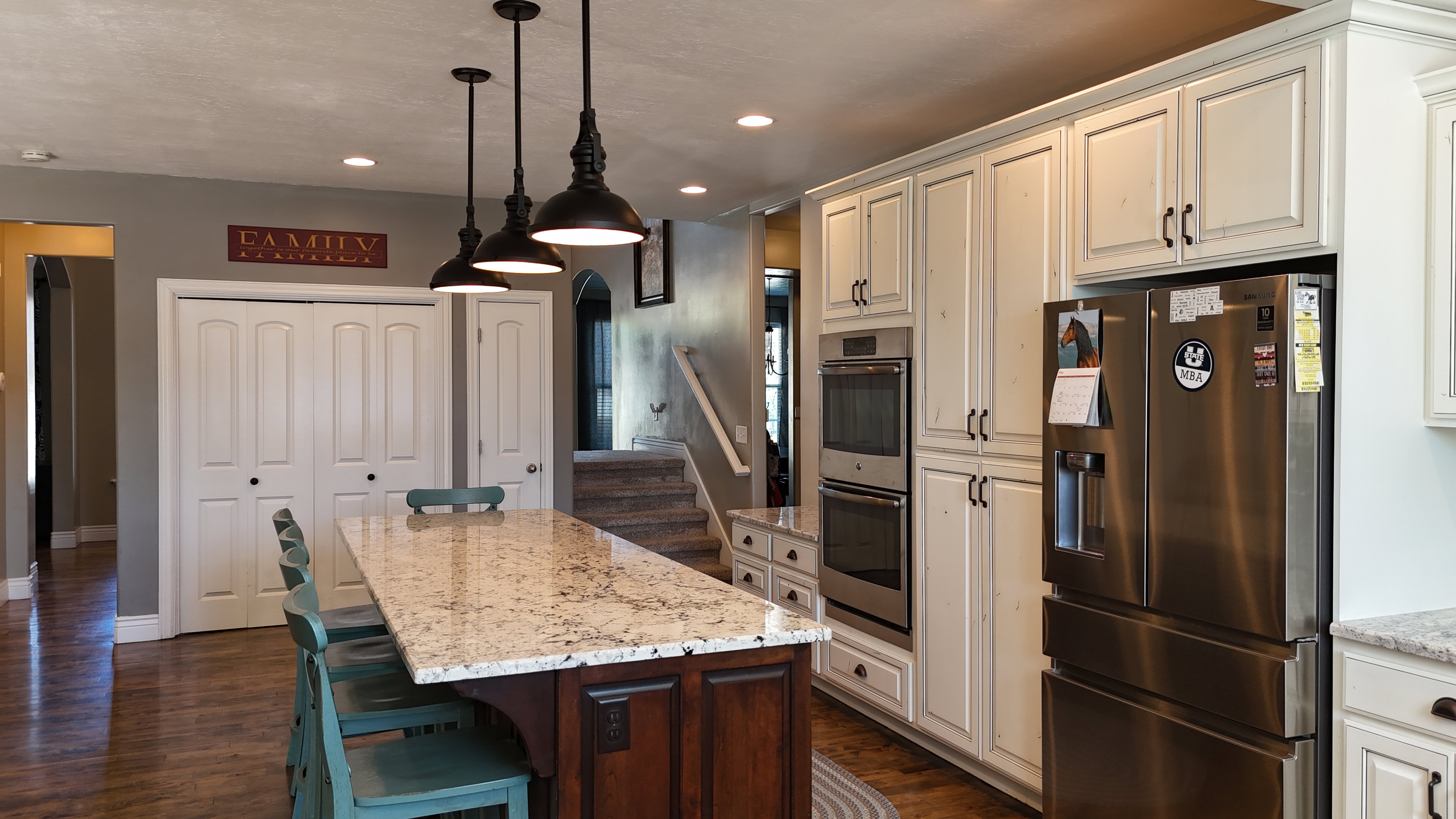 Kitchen featuring a substantial island with a light-toned countertop, wood-finish flooring, recessed lighting, and pendant fixtures