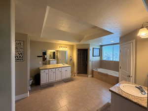 Spacious bathroom featuring a large soaking tub, separate shower enclosure with dark-paneled door, and dual vanities with light cabinetry and granite countertops