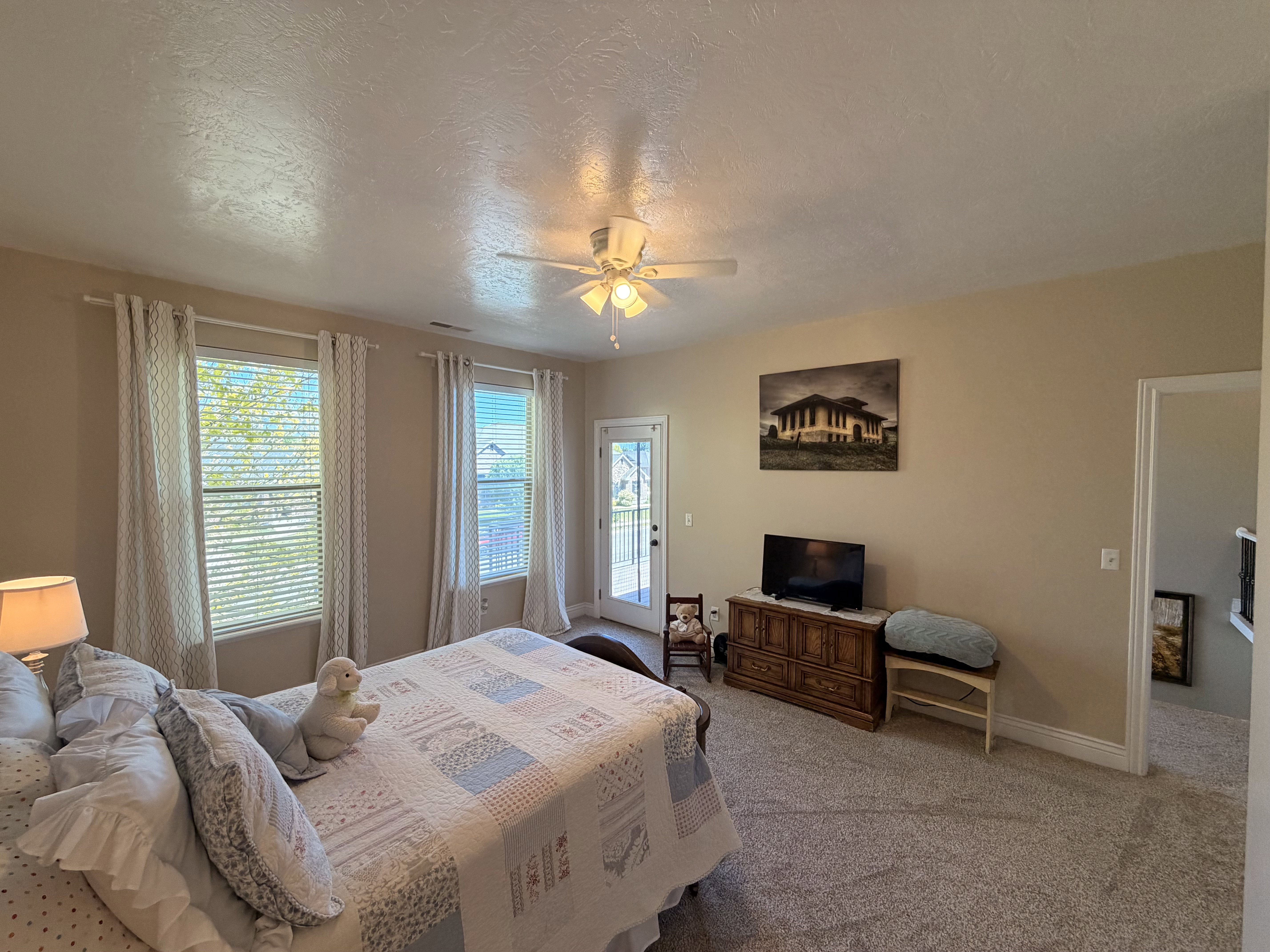 Carpeted room with a ceiling fan, two windows, and a glass-paneled door