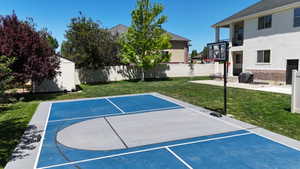 Backyard featuring a sports court with blue and gray surfacing, a basketball hoop, and a privacy fence