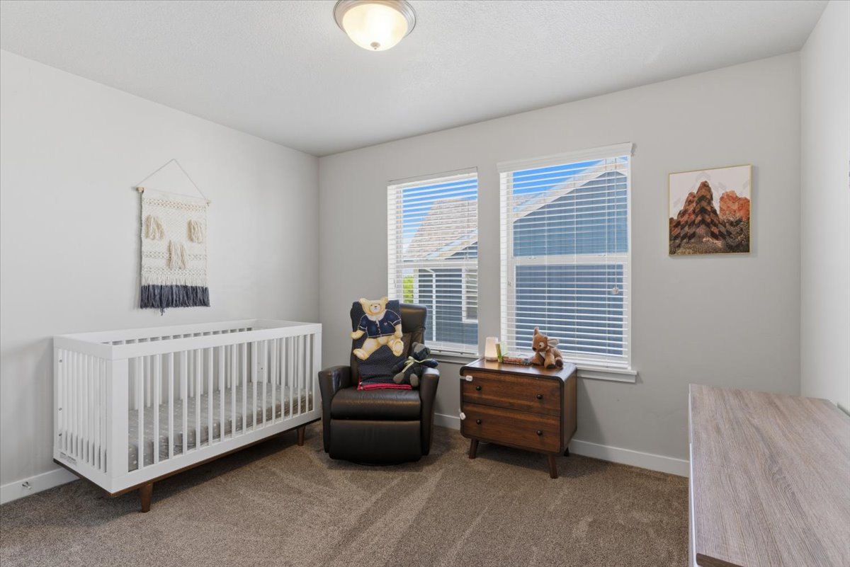 Bedroom featuring neutral-toned walls, plush carpet flooring, and two windows equipped with blinds