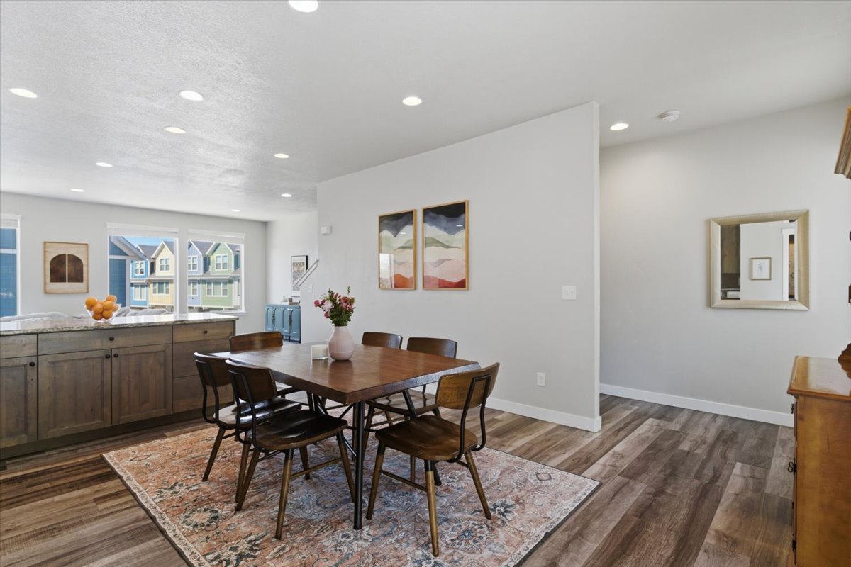 Open-concept dining area featuring wood-finish flooring, recessed lighting, and a built-in kitchen island with stone countertop