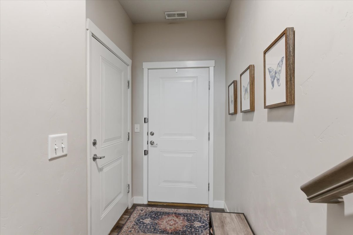 Entryway featuring a paneled door with white trim, wood-finish flooring, and light neutral wall paint