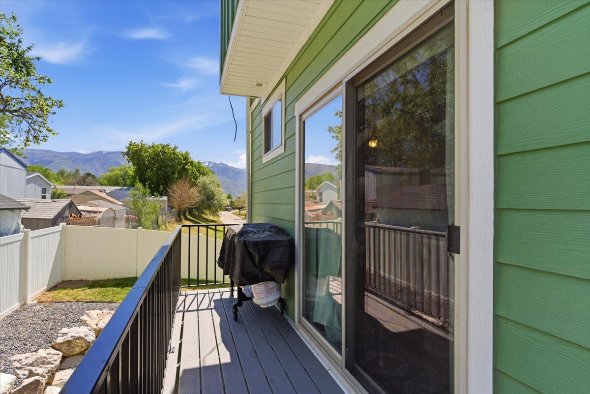Outdoor balcony featuring composite decking, black metal railings, and a sliding glass door