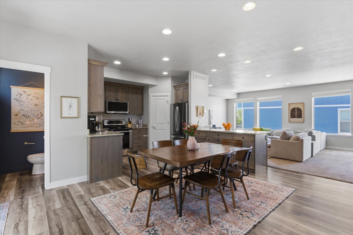 Open-concept living space featuring wood-finish flooring, recessed lighting, and a modern kitchen with a large island and stainless steel appliances