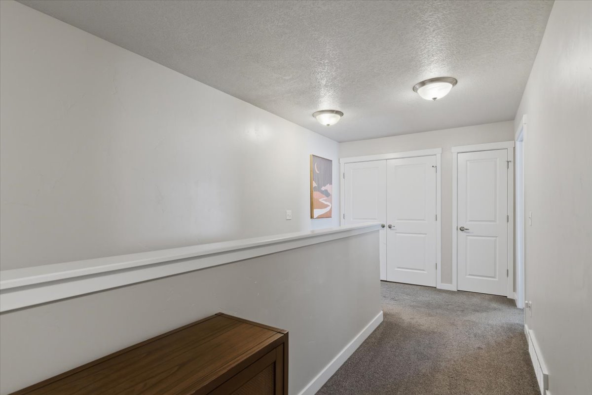 Hallway featuring two-panel interior doors, neutral-toned carpeting, and semi-flush mount ceiling lighting