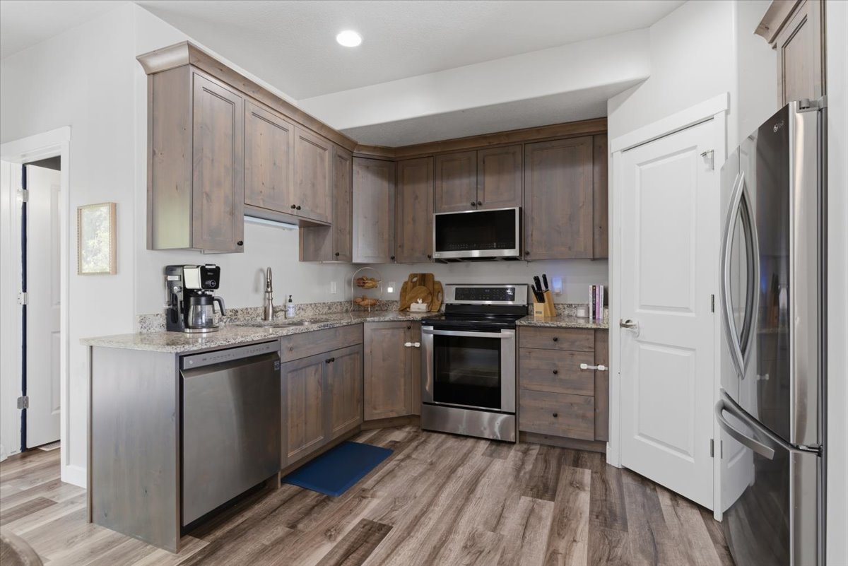 Kitchen featuring wood-finish flooring, light grey cabinetry, stainless steel appliances, granite-style countertops, and recessed lighting